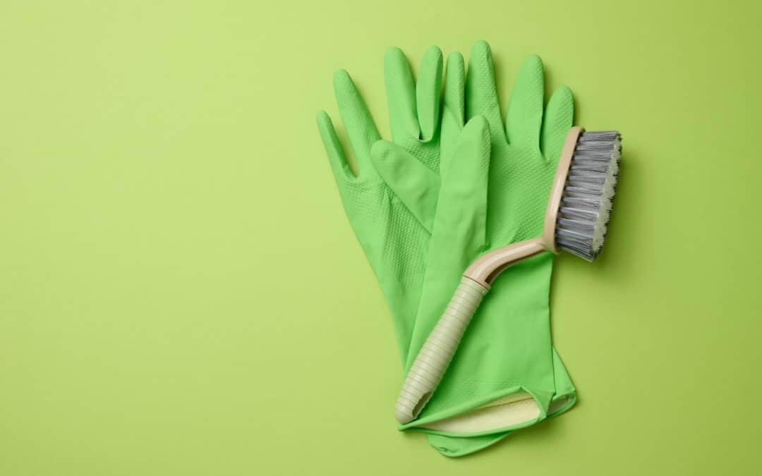 green rubber gloves for cleaning, brushes on a green background